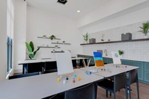 Bright art studio with blank easels, colorful paints, and plants on shelves for a creative workspace ambiance.