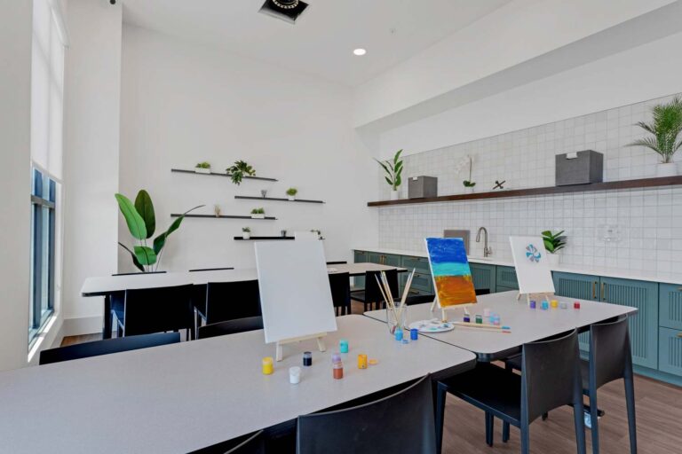 Bright art studio with blank easels, colorful paints, and plants on shelves for a creative workspace ambiance.