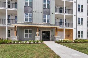 Front view of modern apartment building entrance with landscaping and balconies.