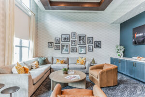 Modern living room with gray sectional, leather chairs, photo wall, and stylish decor. Cozy and contemporary design.