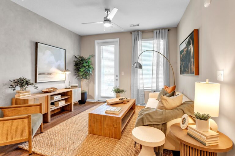 Modern living room with cozy furniture, wooden accents, and natural light from large windows.