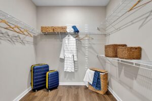 Walk-in closet with baskets, travel suitcases, and a robe on wire shelves.