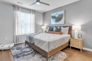 Modern bedroom with wooden bed, cozy pillows, artwork, and warm lighting. Perfect for relaxation and comfort.