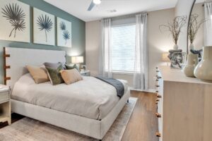 Modern bedroom with cozy bed, stylish decor, and natural light from large window. Neutral tones and elegant furnishings.