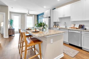 Modern kitchen with granite island, white cabinets, hardwood floor, and dining setup for two on bar stools.