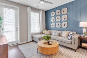 Modern living room with gray sectional sofa, wooden coffee table, blue accent wall, and stylish decor.