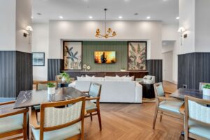 Modern living area with wooden flooring, stylish furniture, and TV; decorative plant artwork on walls.