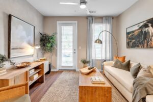Cozy modern living room with neutral tones, wooden accents, and natural light filtering through large windows.