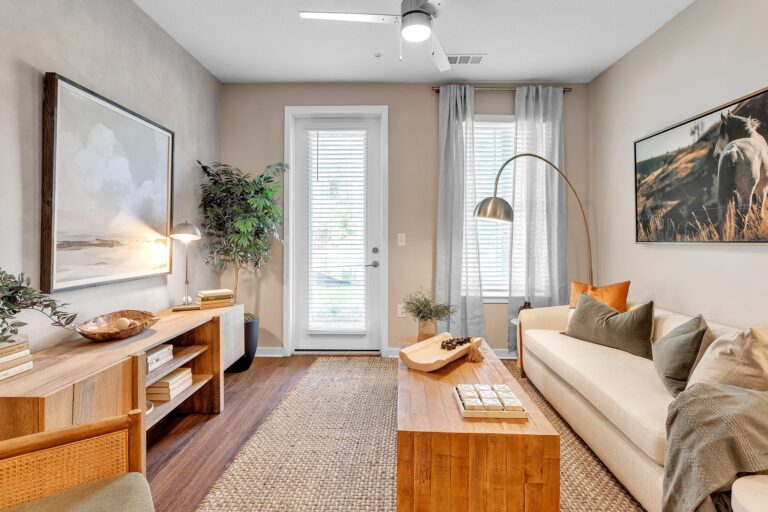 Cozy modern living room with neutral tones, wooden accents, and natural light filtering through large windows.