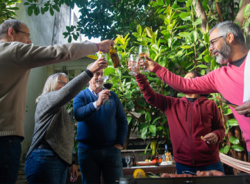 Group of friends toasting and smiling in a lush green garden setting.